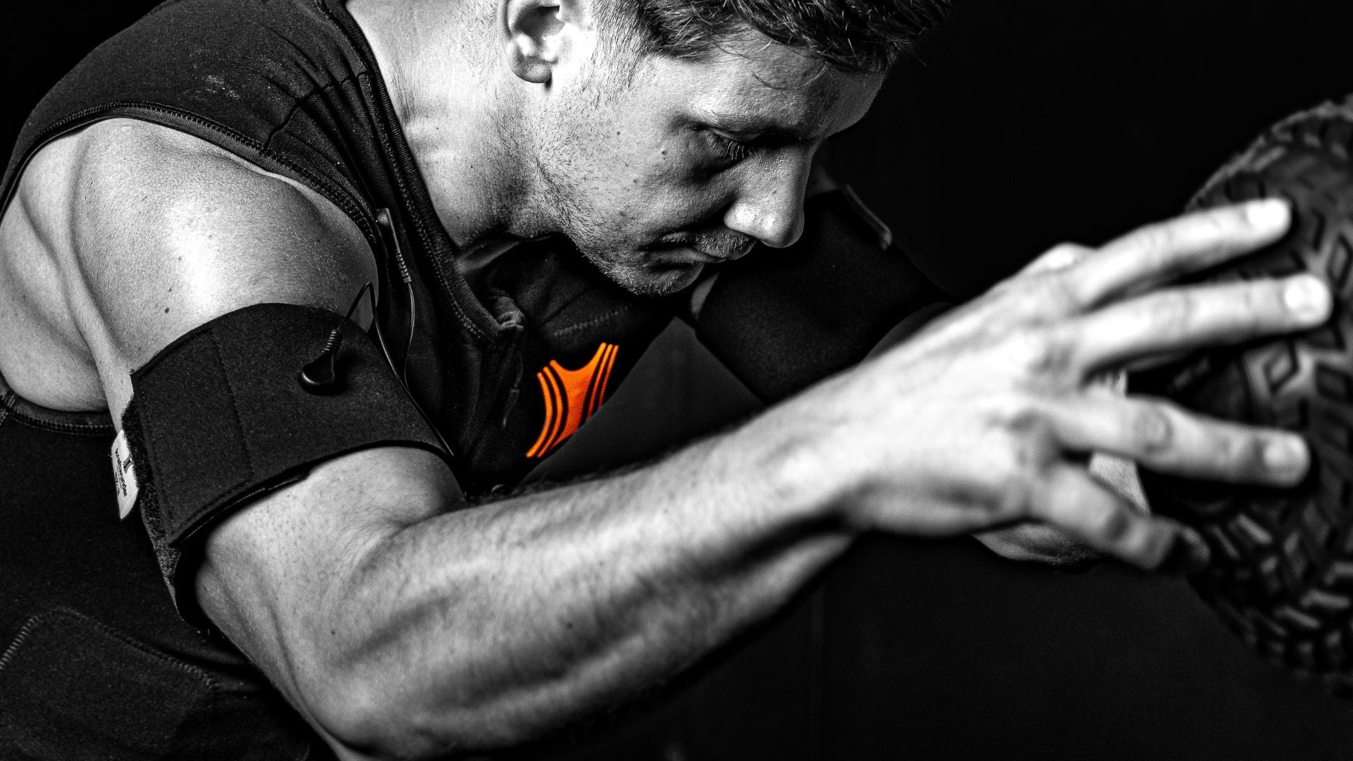 Ein Mann trägt beim Training den Kraftwunder EMA-Anzug und wirft dynamisch einen Gewichtsball, um Muskelkraft und Koordination zu fördern.