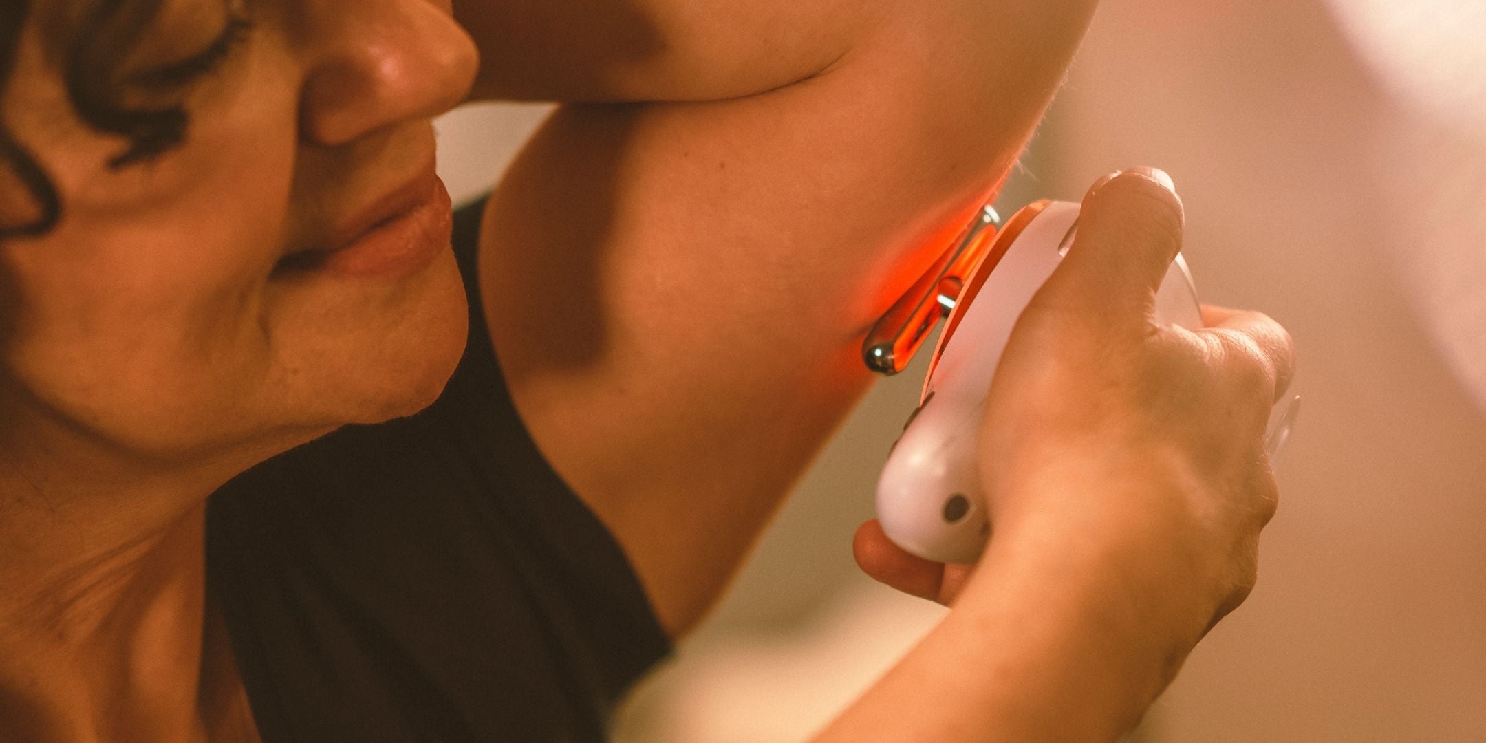 Frau hält sich Evosonics SoundWave Personal an den Oberarm um eine Lymphdrainage gegen schlaffe Oberarme mit Schallvibrationen und Rotlicht durchzuführen. | Therapiegold