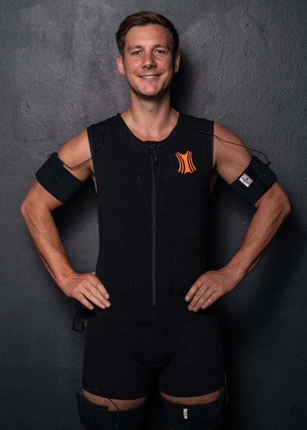 Sportlicher Mann trägt einen schwarzen Kraftwunder EMA-Anzug beim Training, angewendet im Therapiegold-Kontext zur gezielten Elektromyoaktivierung und Leistungsoptimierung.